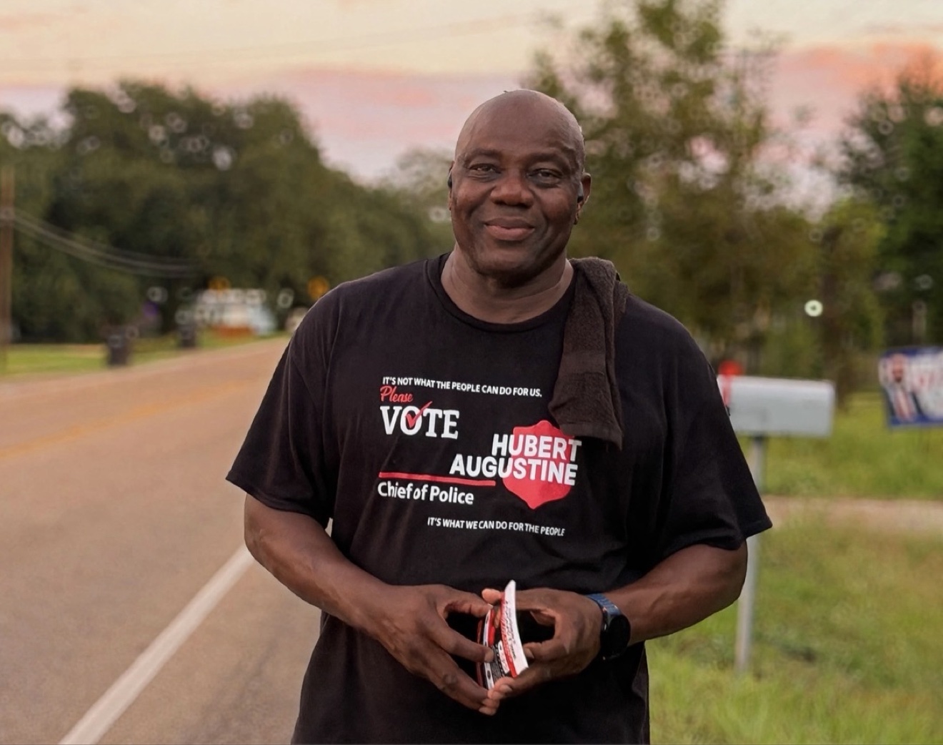 Hubert Augustine talking with voters on a Breaux Bridge street at sunset
