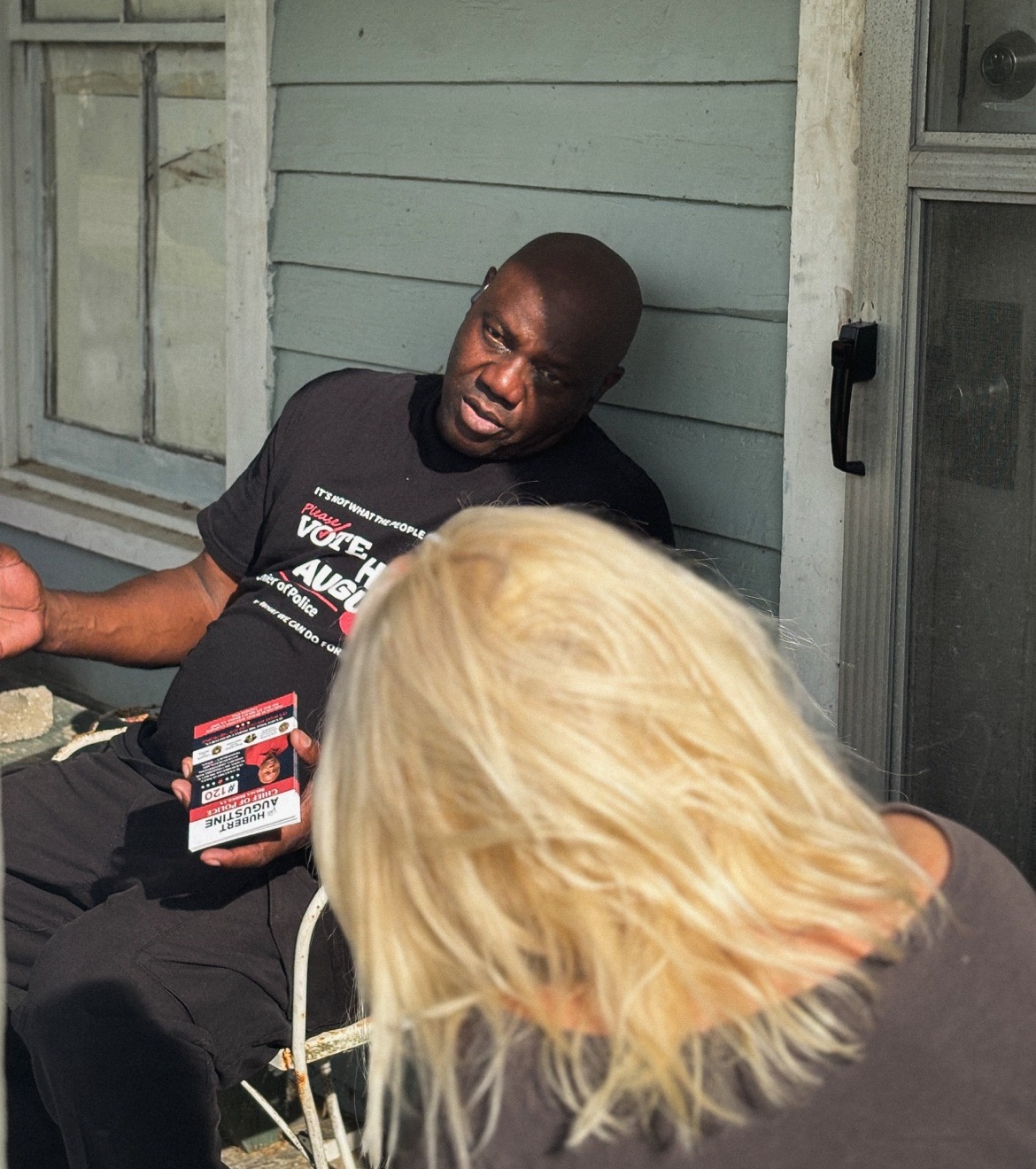 Hubert Augustine talking with a resident on her porch